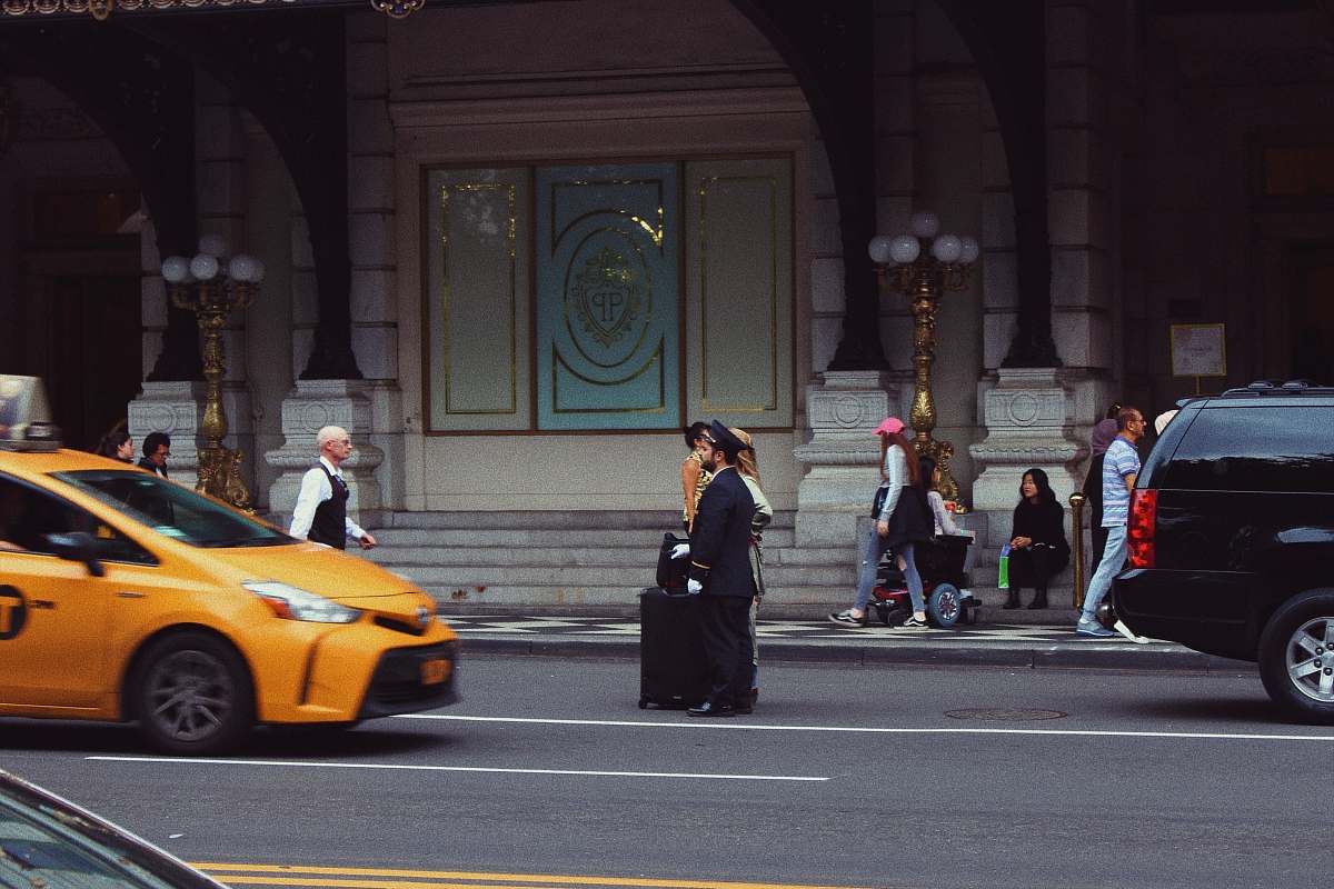 cab people walking on sidewalk during daytime taxi